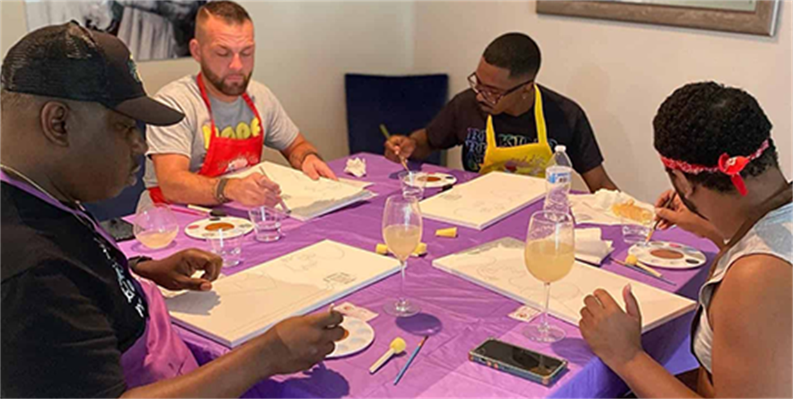 Four adults around a table working on art projects