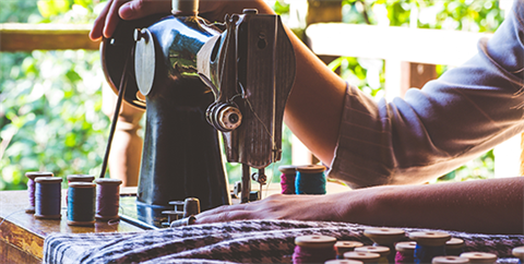 Woman's hand on an antique belt driven sewing machine