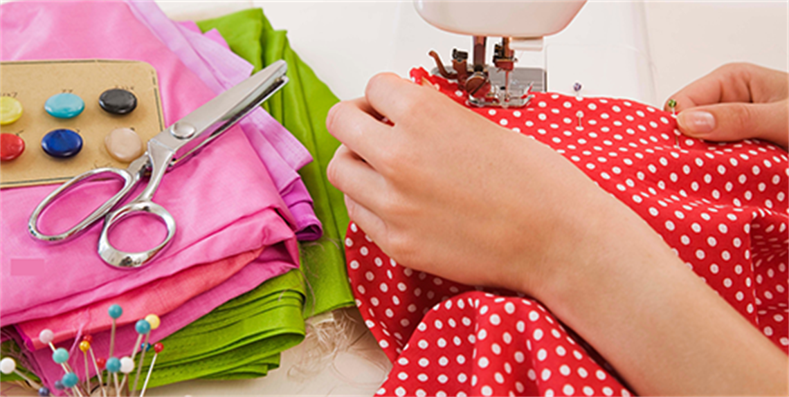 Child's hands pushing cloth through a sewing machine